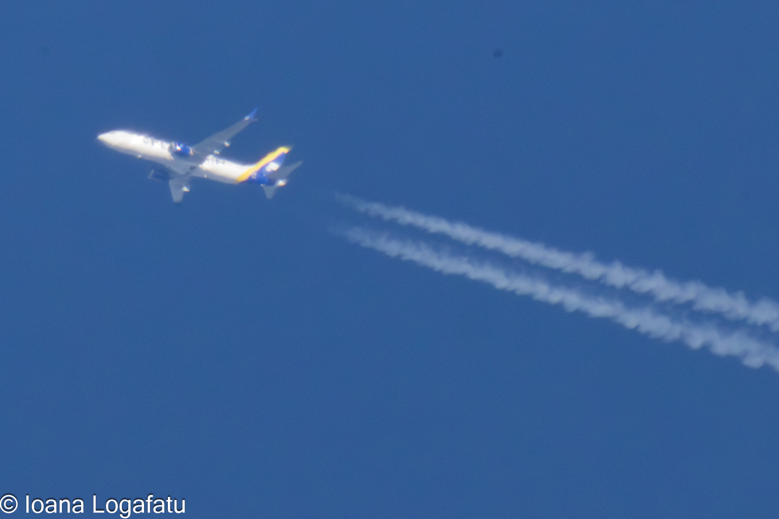 Airplane soaring through the blue sky with trails